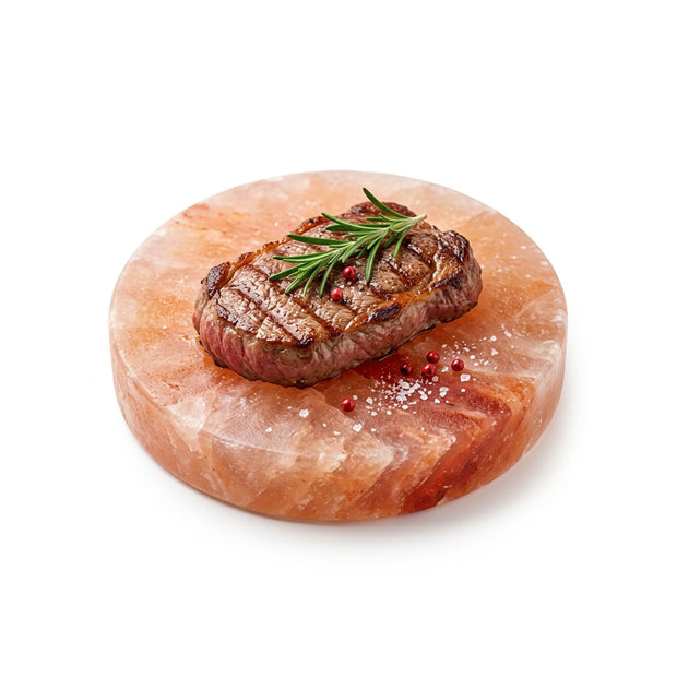 Round Himalayan Pink Salt Cooking Block with grilled steak, rosemary, and peppercorns for BBQ grilling and gourmet cooking